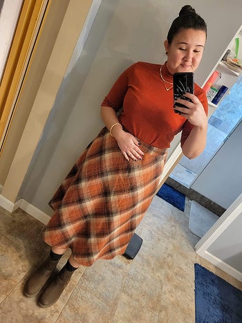 reviewer wearing orange plaid skirt