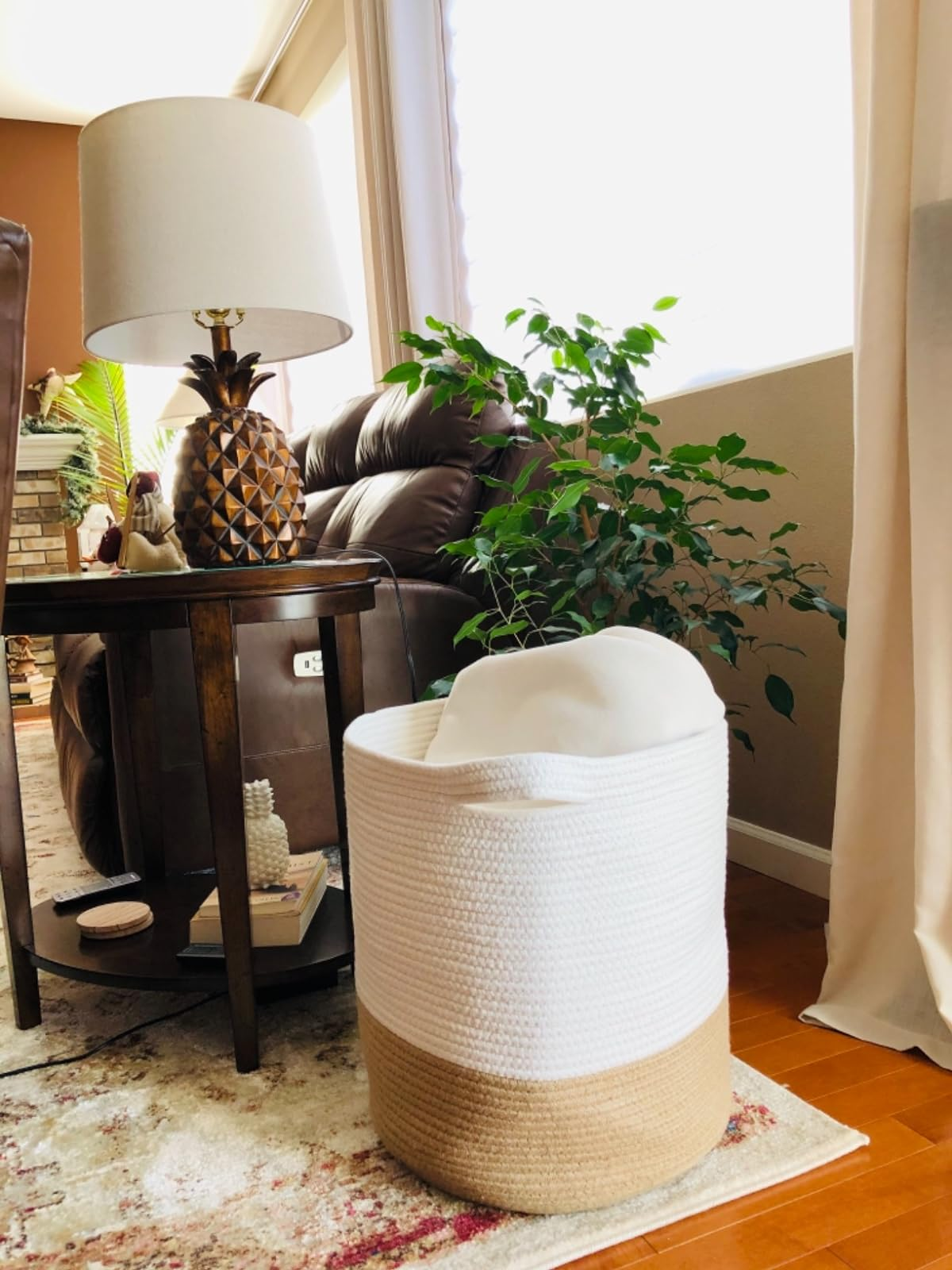 A room with a woven basket, houseplant, lamp on a side table, and a brown sofa