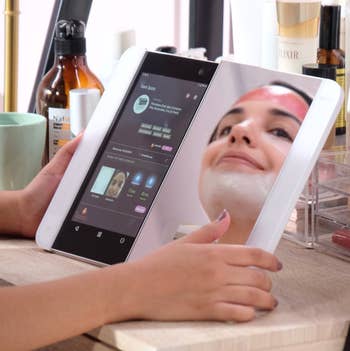 A mirror that is slid out to be half mirror, half touchscreen with a display of apps 