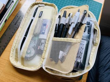 open pencil case with various pens and markers, arranged on a desk for organization and easy access