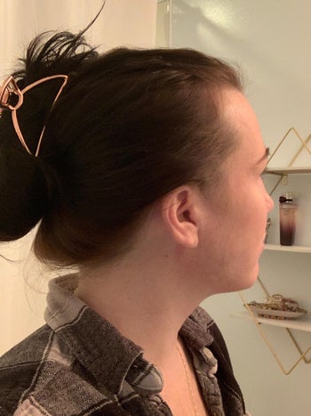 reviewer selfie with the rose gold clip holding up a bun