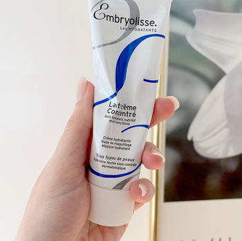 A reviewer holding up the white tube of cream 