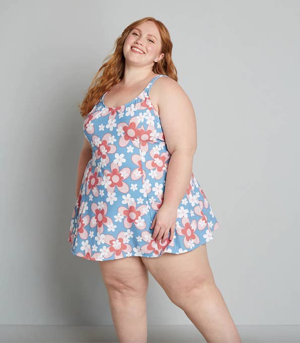 model in blue swim dress with graphic pink and white flowers