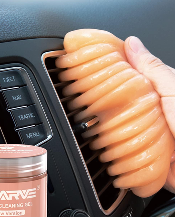 Model using the putty gel to clean a car vent