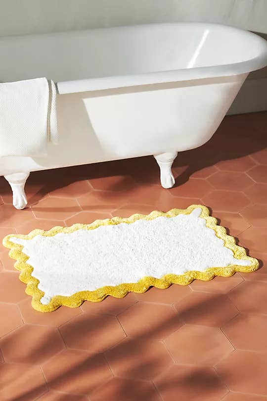 a plush bath pat with yellow trim and curvy edges