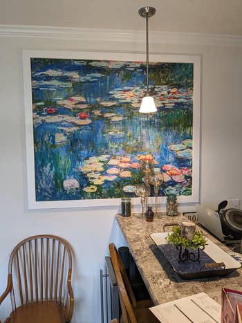 A large, impressionistic coating of h2o lilies connected a eating country partition supra a marble-style antagonistic with a vase and decorative items