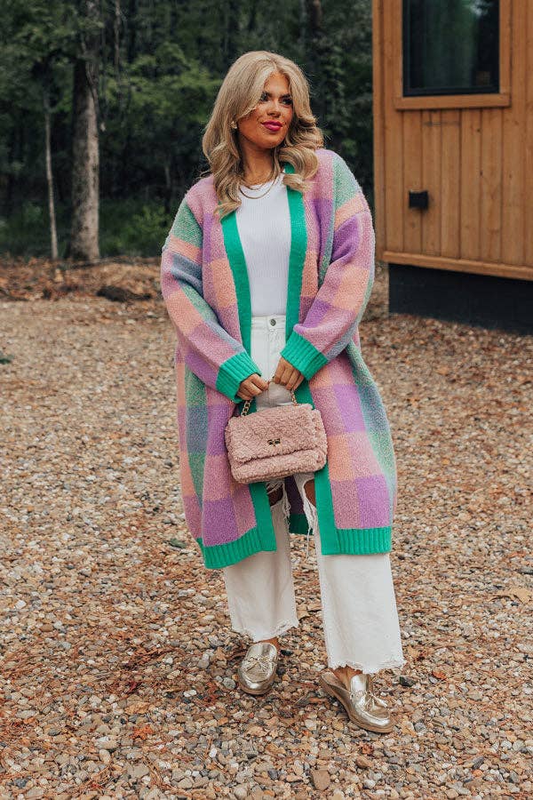 A model posing in the pink, green, and purple cardigan
