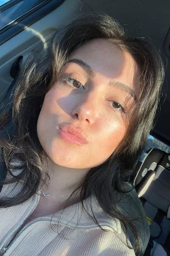Person taking a selfie successful a car, wearing a zip-up casual top, with airy falling connected their face