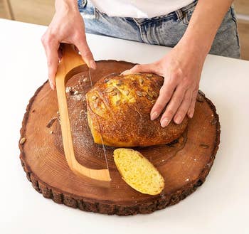 Person slicing bread on a wooden board with a bread knife