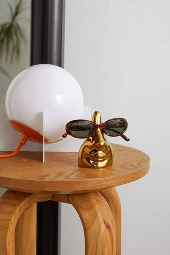 The gold eyeglass holder shaped like a nose and mouth