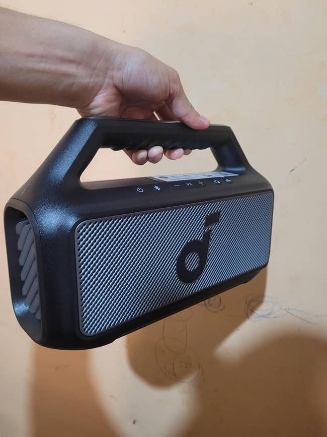 a reviewer holding the portable bluetooth speaker