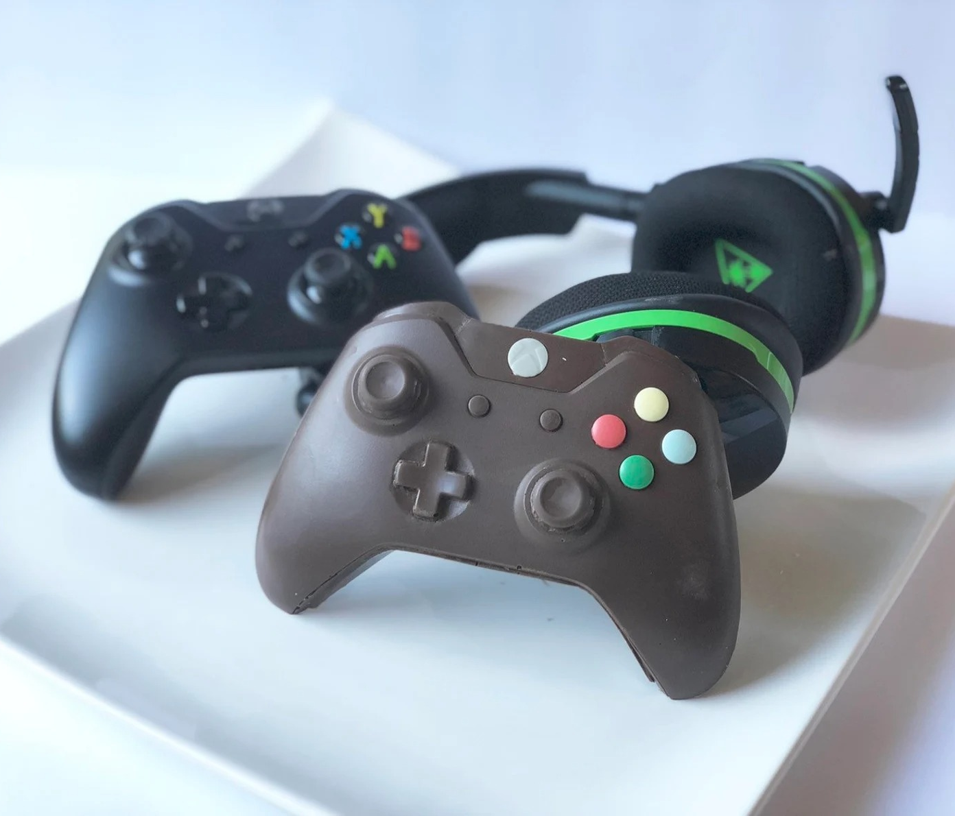 a dark chocolate xbox controller next to the real thing