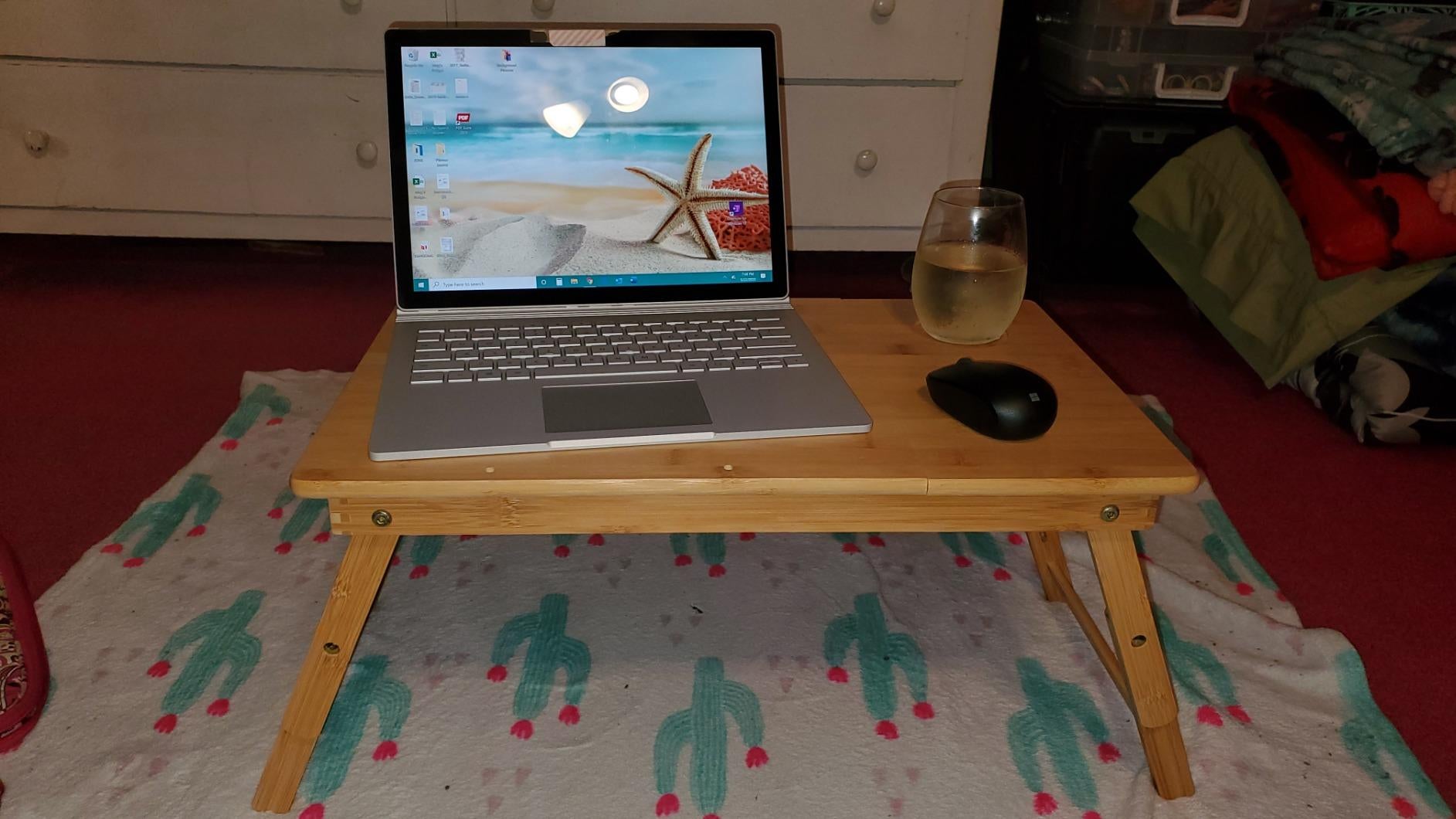 reviewer photo of a standing wooden laptop tray with a laptop, mouse, and drink on top of it
