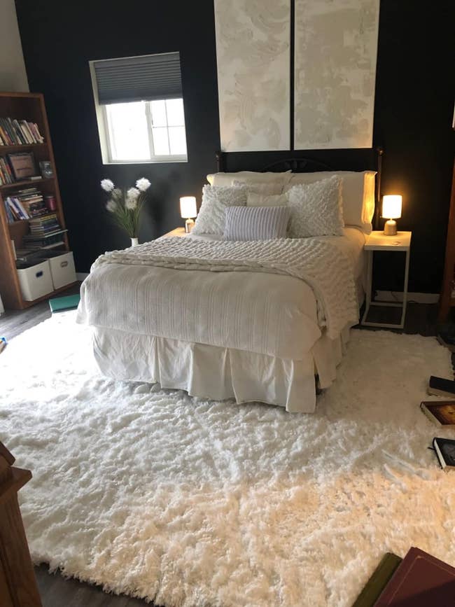 a large white plush rug layered under a bed