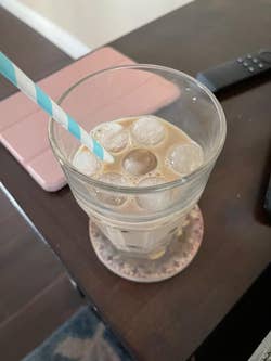 A glass of coffee with ice cubes in it