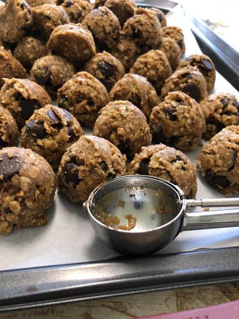 reviewer photo of the cookie scoop next to a tray of uniformly-sized cookie dough balls
