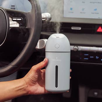 a hand holding a blue humidifier in a car