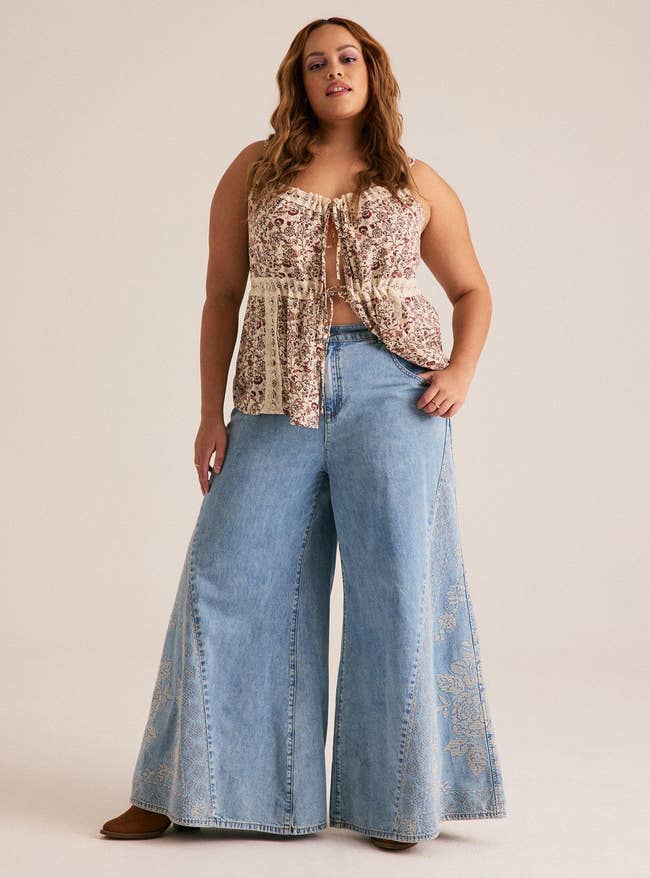 A idiosyncratic   wearing wide-leg denim jeans and a patterned sleeveless top, showcasing a relaxed, vintage-inspired manner  style