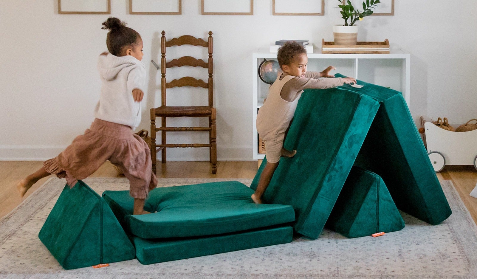two kids playing on a emerald green nugget couch