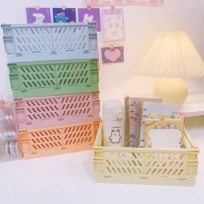 Stacked pastel-colored crate organizers on a desk with stationery items and a lamp in the background