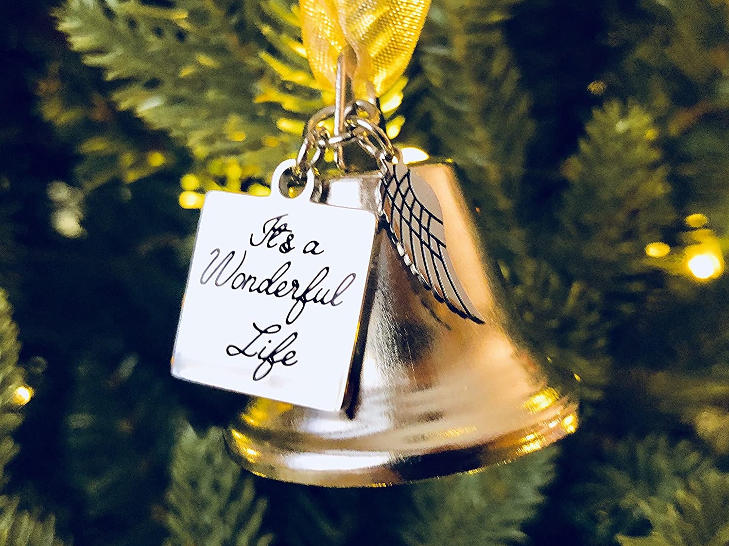 a gold bell with an angel wing charm and a charm that says it's a wonderful life