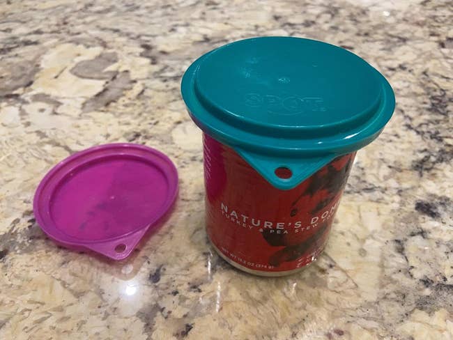 Reviewer photo of the green lid cover on a can of dog food and the pink cover next to it