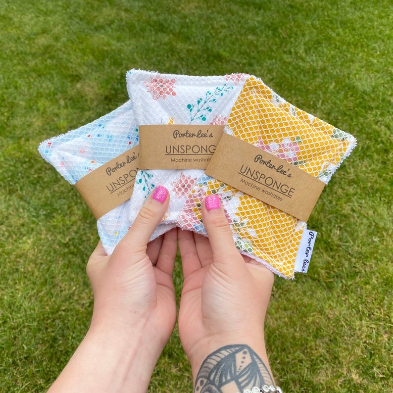 hands holding up three differently printed reusable sponges
