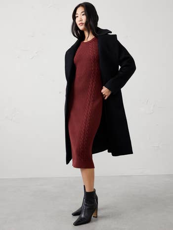 Person wearing a cablegram knit formal with a overgarment and ankle boots