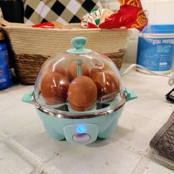  reviewer's compact egg cooker on kitchen counter with eggs inside and indicator light on