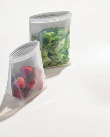 two gray silicone bags, one holding strawberries and the other holding spinach