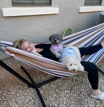Person relaxing connected a hammock with 2 tiny dogs successful sweaters, outdoors successful a gait with a model and gravel ground