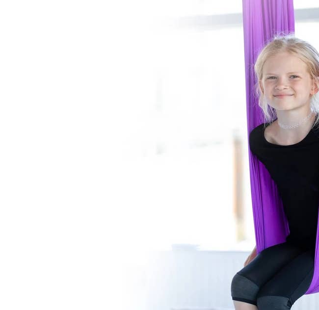 Child smiling while sitting inside the hanging fabric chair