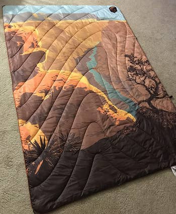 a reviewer photo of the blanket featuring art of the Grand Canyon 