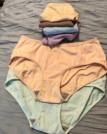 Stack of folded underwear connected a bed, showcasing assorted styles and textures for a buying article