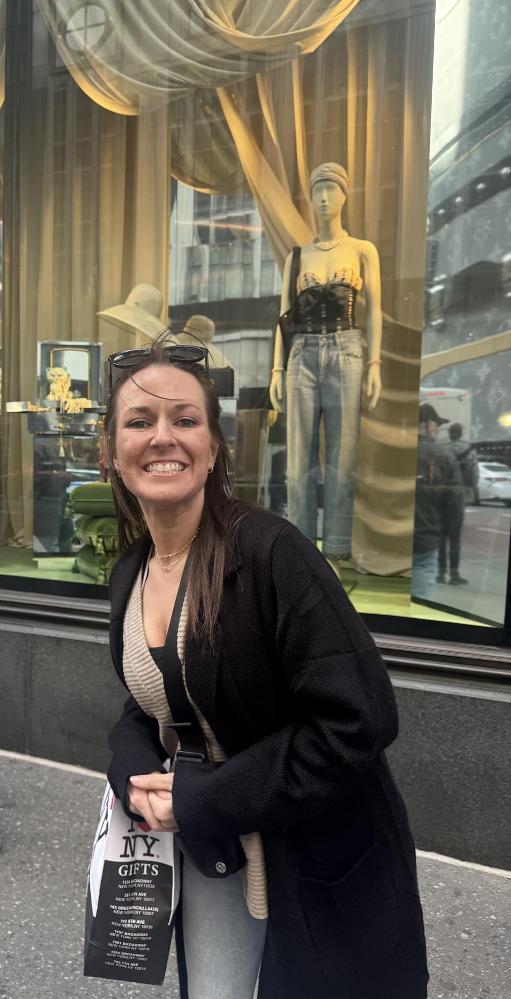 Person smiling successful  beforehand   of a store   show  featuring a mannequin successful  trendy denim and a stylish top