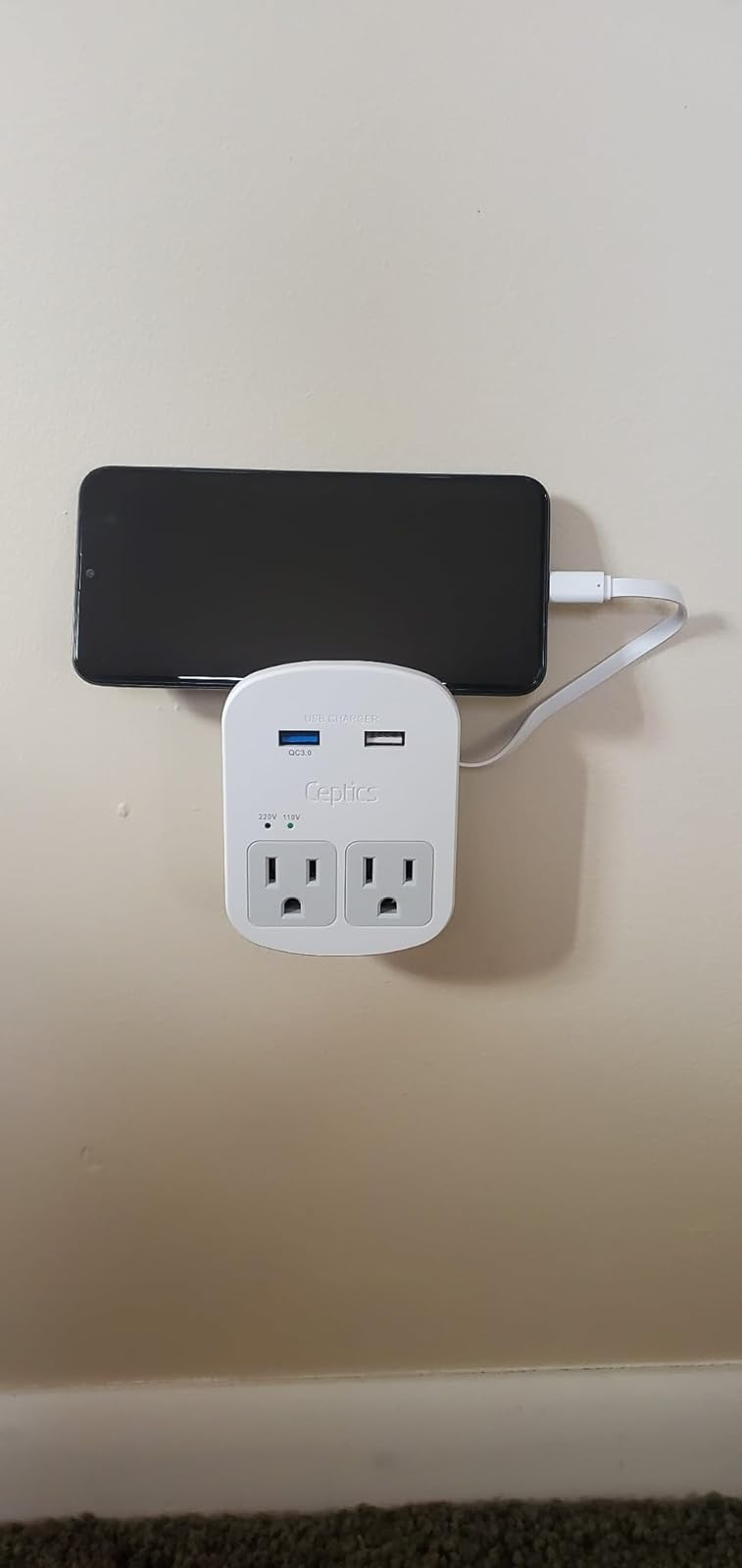 Lifestyle Cell phone associated to a white multi-port charging adapter plugged into a wall outlet