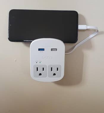 Lifestyle Cell phone associated to a white multi-port charging adapter plugged into a wall outlet