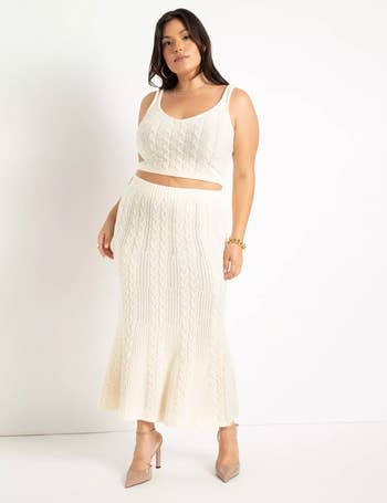 a model wearing a matching white cable knit tank top and midi skirt with nude heels