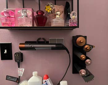 Perfume bottles and hairsbreadth  styling tools, including a Dyson Airwrap set, arranged connected  a partition  shelf
