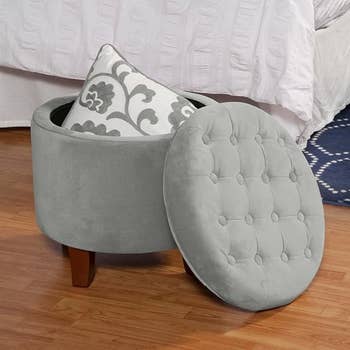Round retention  ottoman with woody  legs, unfastened  to uncover  a cushion inside. Ideal for compact surviving  spaces