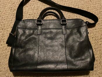 Leather Fossil container with handles and a enarthrosis strap connected a carpeted floor