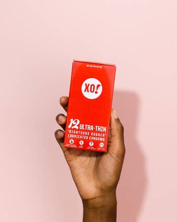 hand holding red box of xo ultra-thin condoms