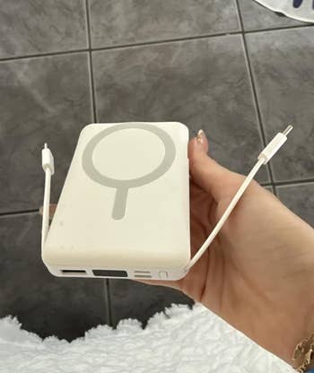 A idiosyncratic   holds a MagSafe-compatible powerfulness  slope  with attached USB-C cables, suitable for charging devices connected  the go