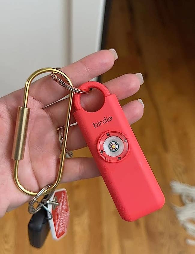 A reviewer holding the pink Birdie attached to a keychain