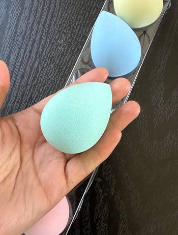 reviewer holding teal beauty sponge
