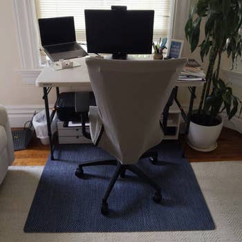 a desk set up up with a rolling chair and the mat in blue