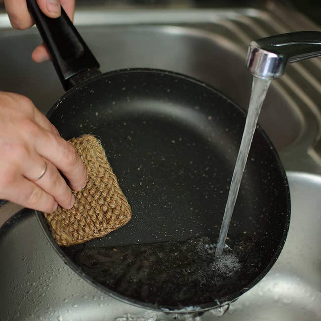 a model washes a pan in a kitchen sink using the natural hemp sponge