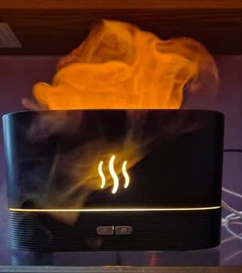 A black humidifier with lights mimicking flamse coming out of it 