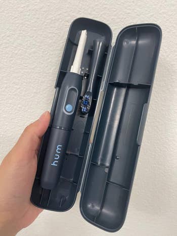a reviewer holding the grey toothbrush in its case