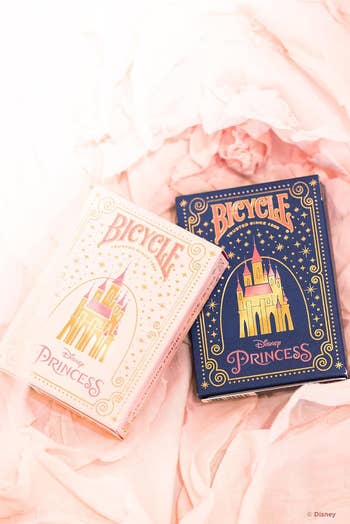 Two decks of Bicycle Disney Princess playing cards, 1  successful  airy  packaging and the different   successful  dark, featuring a castle plan  connected  the covers